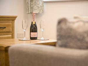 a bottle of wine sitting on a table with two glasses at Foxwhelp in Ledbury