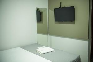 a room with a bed with a flat screen tv at Mimari Hotel in Tangara da Serra
