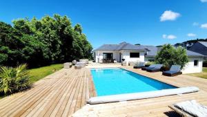 a backyard with a swimming pool and a wooden deck at Villa des Abers vue mer, GR34, piscine chauffée in Landéda
