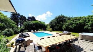 a swimming pool with a table and chairs next to it at Villa des Abers vue mer, GR34, piscine chauffée in Landéda +59 photos