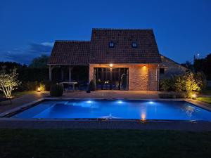a swimming pool in front of a house at night at Gezellig huisje met zwembad en sauna in Ellezelles - Bellezelles in Ellezelles