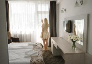 a woman standing in a hotel room looking out the window at Hotel Magnólia in Piešťany