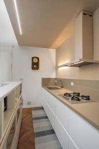 a kitchen with white cabinets and a sink and a clock at La Casa sui Colli in Bologna