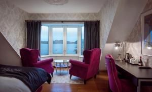 um quarto com uma cama e cadeiras, uma secretária e uma janela em Hotel Wassilioff - Unike Hoteller em Stavern