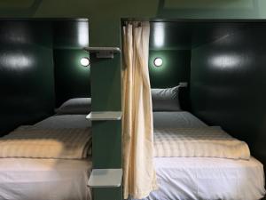 two beds in a bedroom with green walls at Cheevit Cheeva Koh Tao Hostel in Ko Tao