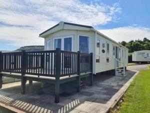 a mobile home with a porch and a deck at Sea View Platinum Caravan in Llanddulas