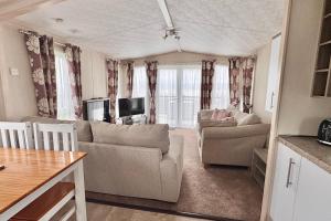a living room with a couch and a tv at Sea View Platinum Caravan in Llanddulas