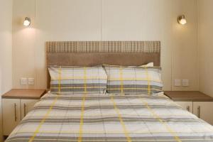 a bedroom with a bed with blue and yellow stripes at Sea View Platinum Caravan in Llanddulas
