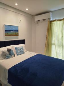 a bedroom with a blue and white bed and a window at Mar à vista in São Luís +55 photos