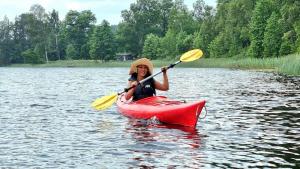 a woman in a red kayak on a lake at Björklunda, lakes, canoe, sauna in Näfstorp