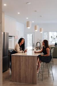 two women sitting at a kitchen island with wine glasses at Chalet Gratitude with Private SPA & Sauna in Saint Come
