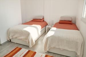 two beds in a room with white walls at Casa del Bienestar in Lanjarón +39 photos