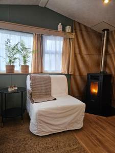 a bedroom with a white bed and a stove at Olm29 Vakantiewoning in het Drents Friese Wold vlakbij Diever Zwembad, Animatie, Restaurant, Wandelen, Natuur in Oude Willem