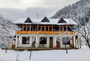 a house with snow on top of it at Peace homestay n cafe in Kalgha
