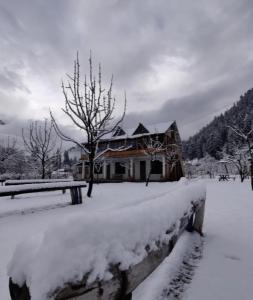 a house covered in snow in front at Peace homestay n cafe in Kalgha +10 photos