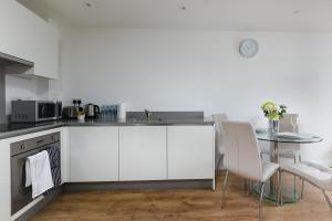 a kitchen with white cabinets and a table with chairs at Charming 1Bed Flat with Private Balcony, Super Double Bed, Free Allocated Parking, and Easy Access to Tube & Central London in Enfield +3 photos