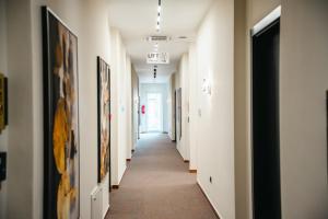 a hallway with white walls and a long hallway with paintings at Stars Hotel in Jelah