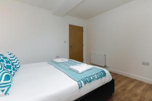 a white bed with two towels on top of it at Charming 1Bed Flat with Private Balcony, Super Double Bed, Free Allocated Parking, and Easy Access to Tube & Central London in Enfield