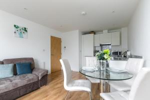 a living room with a glass table and white chairs at Charming 1Bed Flat with Private Balcony, Super Double Bed, Free Allocated Parking, and Easy Access to Tube & Central London in Enfield