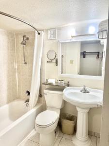 a bathroom with a white toilet and a sink at Executive Inn - Fort Lee in Fort Lee +9 photos