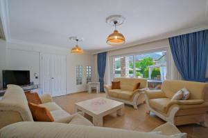 ein Wohnzimmer mit Sofas, Stühlen und einem Fernseher in der Unterkunft Villa Brezza in Fethiye