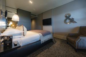 a hotel room with a large bed and a chair at Dakota Edinburgh in Queensferry