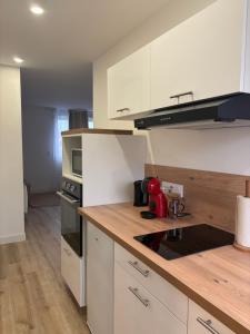 a kitchen with white cabinets and a wooden counter top at Charmant Appartement Moderne B in La Roche-sur-Yon
