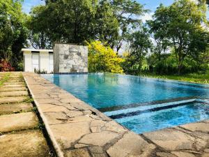a swimming pool with blue water in a yard at Kadulla Resort in Habarana