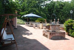 a patio with an umbrella and a bench and tables at Independent accommodation on Etna in San Giovanni Montebello