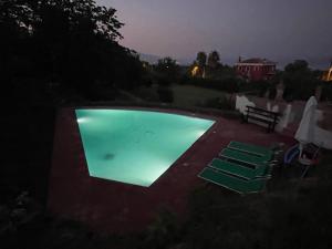 a swimming pool at night with two green chairs at Independent accommodation on Etna in San Giovanni Montebello