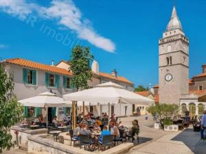 a group of people sitting at tables with a clock tower at Villa Sbay in Omišalj