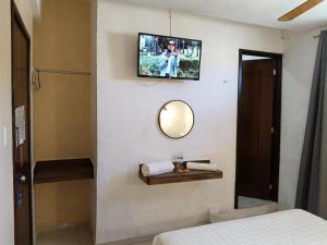 a room with a tv on a wall with a bed at Hotel Rath in Campeche