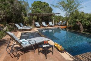 a swimming pool with chairs and a table next to it at Kariega Game Reserve Main Lodge in Kenton on Sea