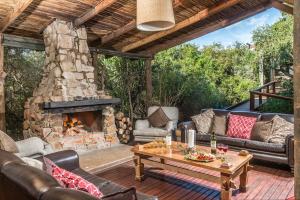 a patio with couches and a stone fireplace at Kariega Game Reserve Main Lodge in Kenton on Sea