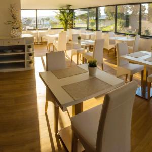 a restaurant with white tables and white chairs and windows at Hotel Lara in Valença
