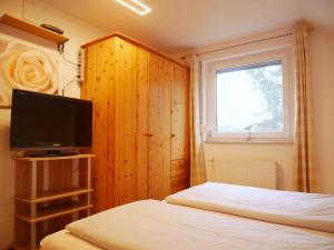 a bedroom with a bed and a tv and a window at Robby2 in Kaltenhof