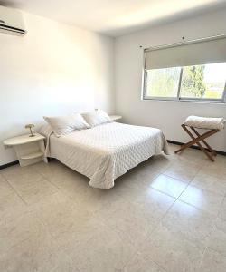 a white bedroom with a bed and a window at R Haus 2 Con Cochera in Concordia