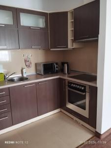 a kitchen with brown cabinets and a sink and a microwave at APARTAMENT W CENTRUM OLESNA in Olesno