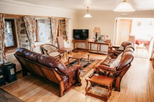 a living room with leather furniture and a television at The Barn B&B in Margam