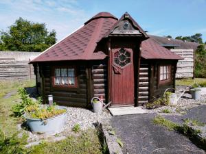 a small wooden cabin with a red door in a yard at Magic Kota - Sternenguckerhaus in Wilhelminenthal