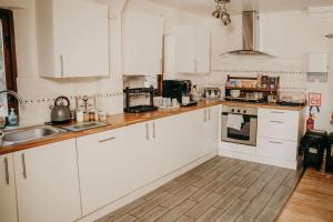 a kitchen with white cabinets and a sink at The Barn B&B in Margam