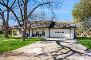 a house with a tree and a driveway at Stunning Rivrefront 3BR with Hot tub, water view! in Seguin