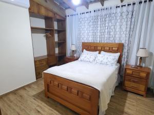 a bedroom with a large wooden bed with white sheets at Villa Rosalía con Piscina Climatizada in Jarabacoa +45 photos