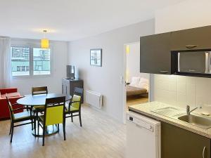 a kitchen and dining room with a table and chairs at Terres de France - Appart Hôtel Rouen Flaubert in Rouen