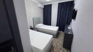 a small bathroom with two beds and a toilet at Birinci Hotel in Mingachevir