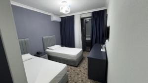 a small room with two beds and a desk at Birinci Hotel in Mingachevir