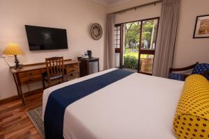 a bedroom with a bed and a desk and a television at Bronte Hotel in Harare +8 photos