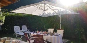 a table and chairs under a white umbrella at B&B AI PELLEGRINI in Villa Santina