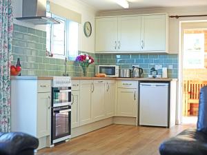 a kitchen with white appliances and blue tiles at Tom Putt in Ledbury
