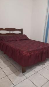 a bed with a red comforter on top of it at José Nilton in Imbituba